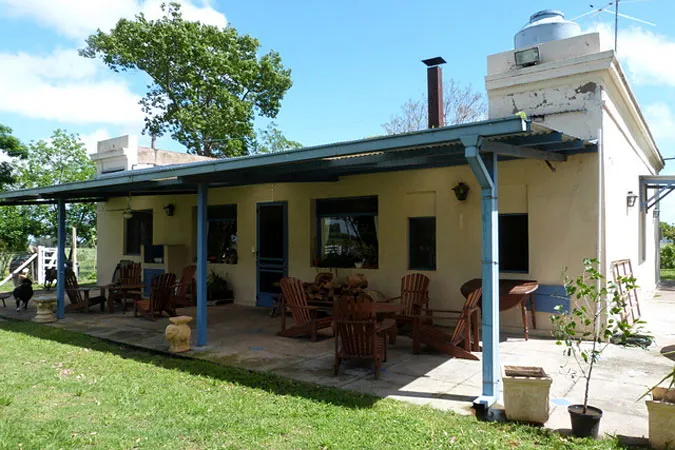 La galería techada de la casa, con sillones de madera, dando al jardín